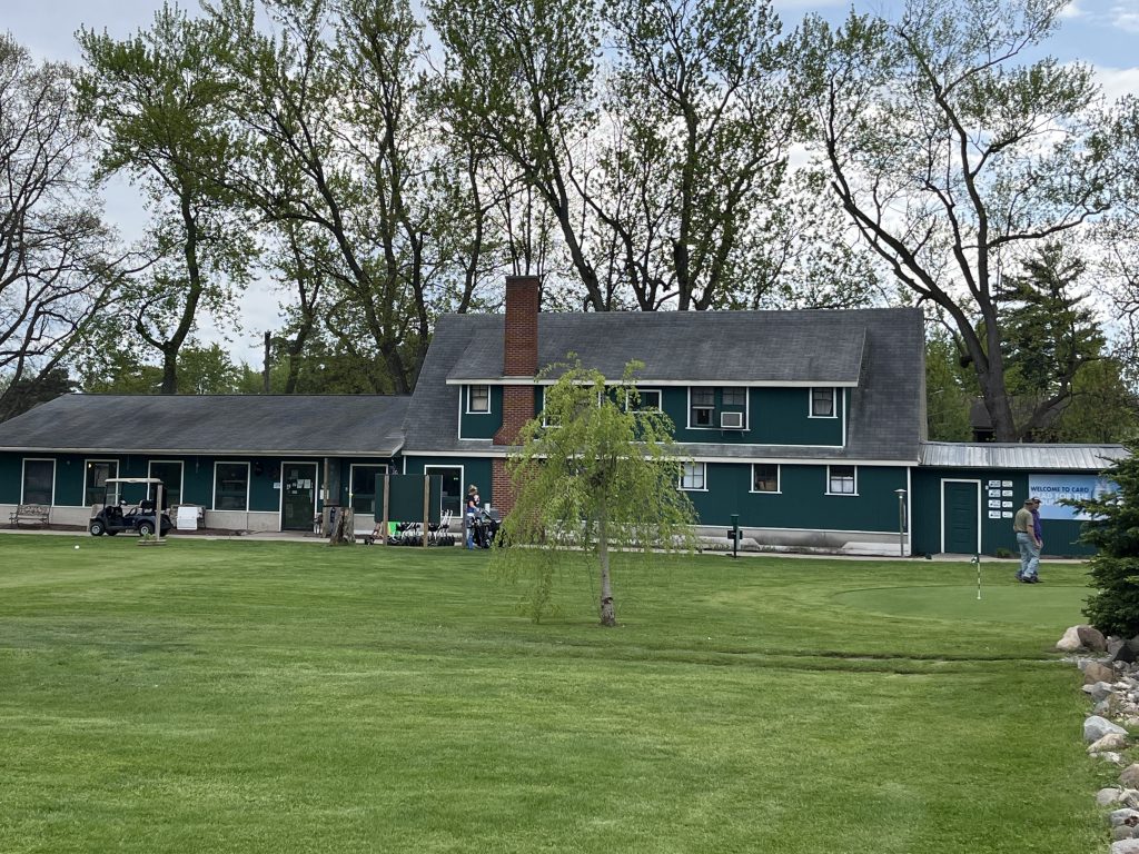 Caro Golf Club's green clubhouse beside the putting green